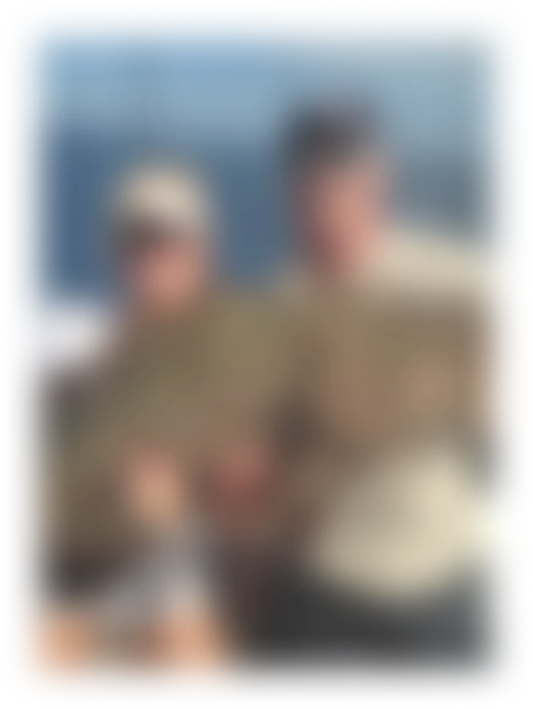Two people on a boat holding a very large fish with the ocean in the background.