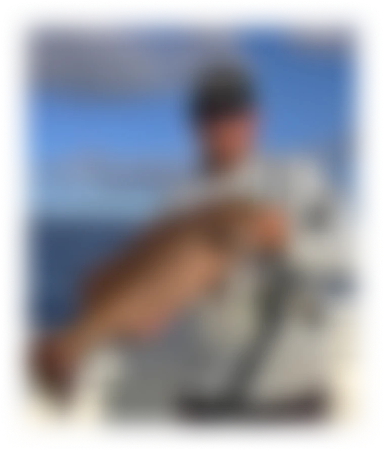 Man on a boat holding a large orange and pink fish with the ocean and a cloudy sky in the background.