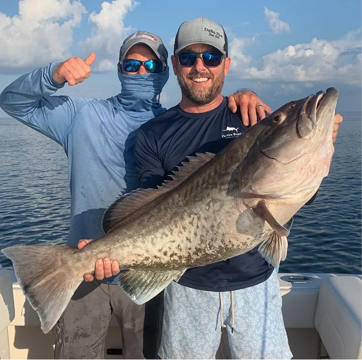 Two smiling anglers on a Fintastic Fishing Charters boat holding a massive Gag Grouper caught offshore.