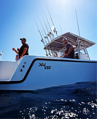 Two fishermen on a SeaVee boat with fishing rods, enjoying a sunny day on the water.