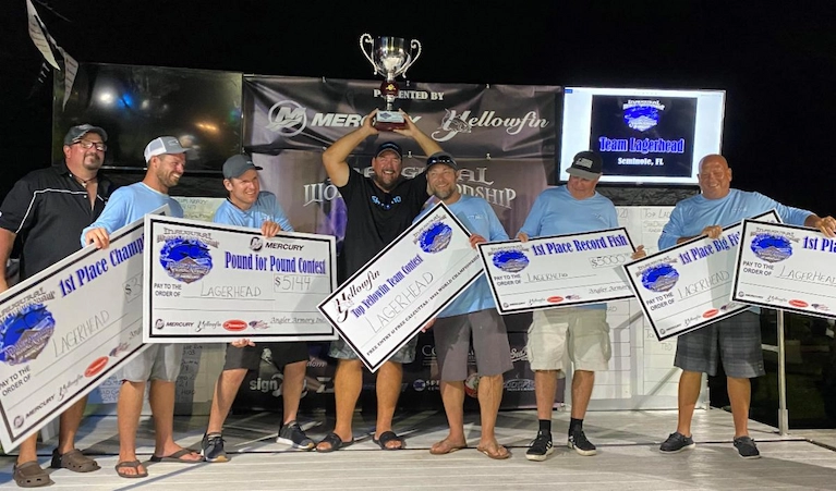 Team Lagerhead stands on stage holding large prize checks and a trophy at a night fishing tournament award ceremony.
